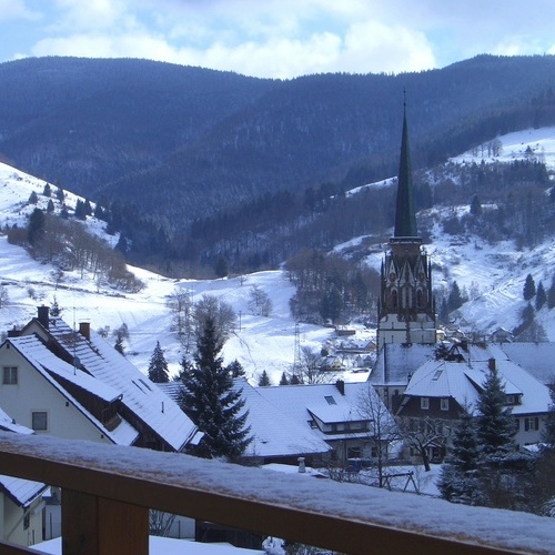 Balkon mit Panoramablick auf das verschneite Sch&ouml;nau mit dem Kirchturm der Maria Himmelfahrtskirche - 