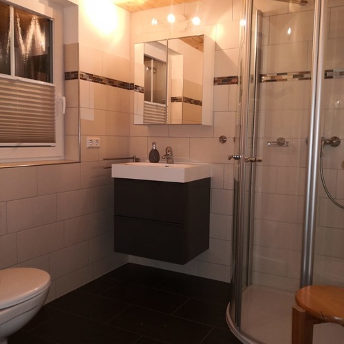 Badezimmer mit Eckdusche, Waschbecken und Toilette sowie einem Fenster  - 