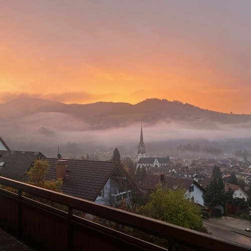 Blick vom Balkon auf den orangef&auml;rbten Abendhimmel &uuml;ber Sch&ouml;nau - 