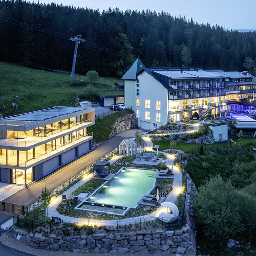 Au&szlig;enansicht Belchenhotel J&auml;gerst&uuml;ble - Au&szlig;enansicht des Belchenhotel J&auml;gerst&uuml;ble mit Au&szlig;enpool und Beleuchtung in der D&auml;mmerung 